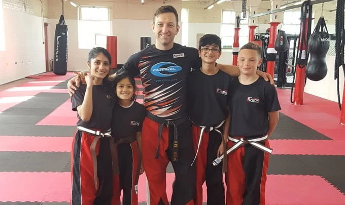 Young kickboxers posing for a picture with their Sensei