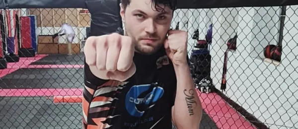 Man standing in a cage, throwing a punch towards the camera